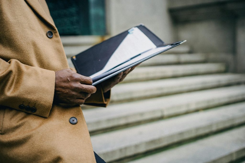 Stilvoller Mann im Mantel mit einem Ordner auf der Stadttreppe, der Professionalität verkörpert.