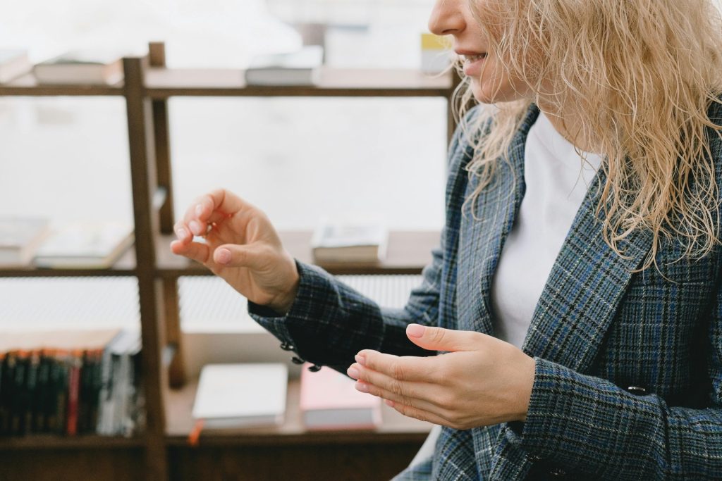 Berufstätige Frau, die in einem modernen Büroumfeld an einem Geschäftsgespräch teilnimmt und mit den Händen gestikuliert.